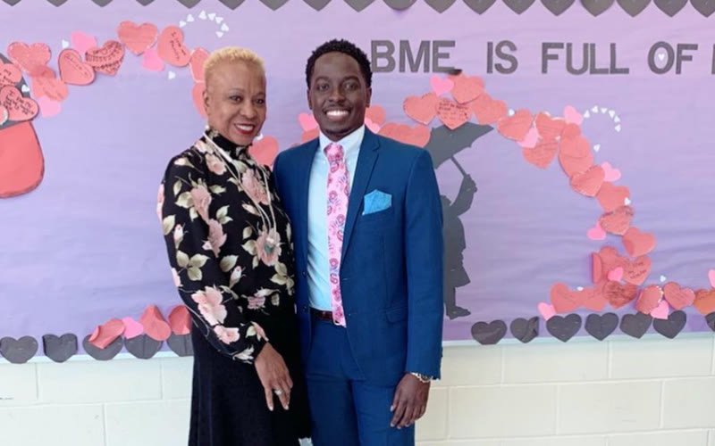 Phillip Karaya with an educator in front of a Browns Mill Elementary bulletin board on Career Day