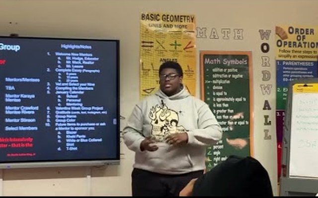 A student presenting goals to the class in front of a mentor group slide